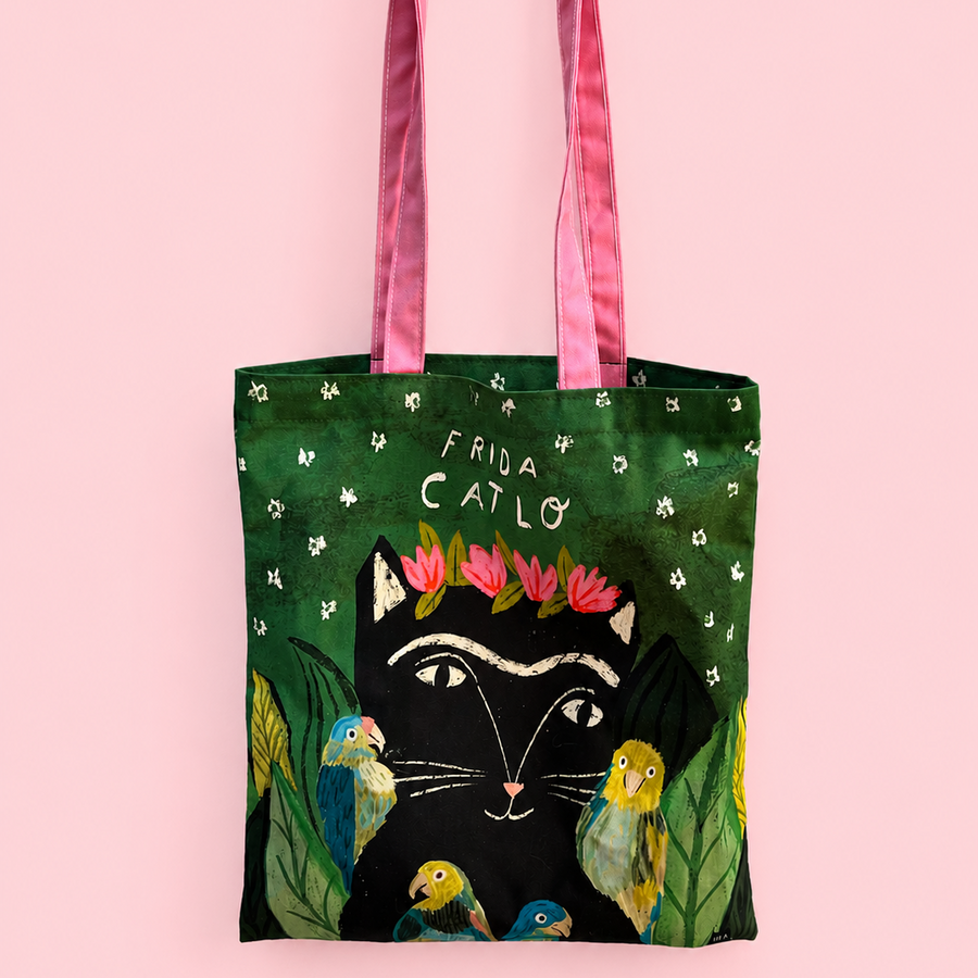 A fabric tote bag with pink satin handles, featuring a design of a black cat wearing a pink flower crown