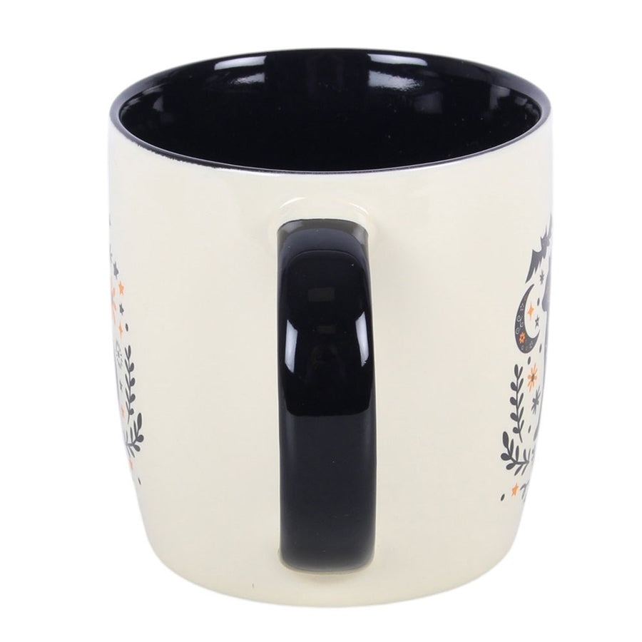 Frightful Folk Cat Mug showing black handle and interior, cream ceramic with folk art design visible on reverse