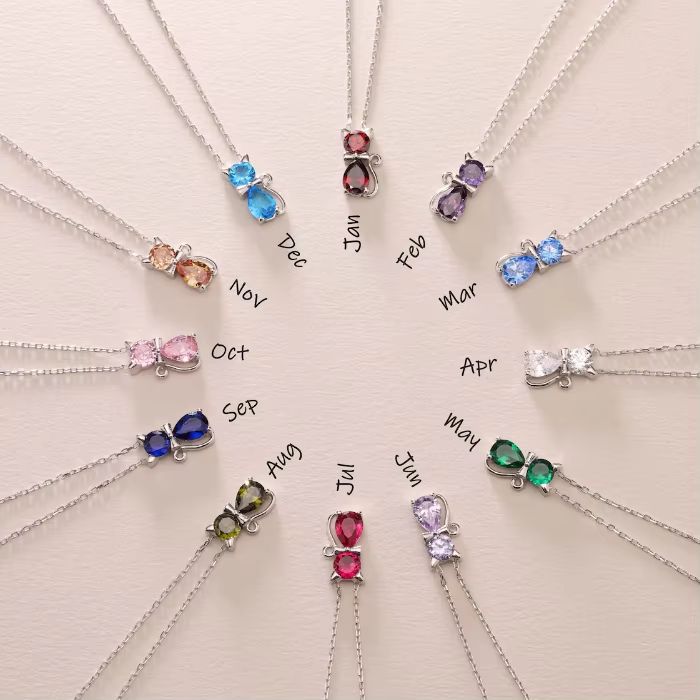 A collection of cat-shaped birthstone pendants, each pendant is a different colour representing birth months