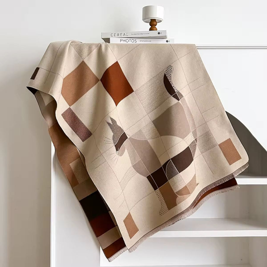 Beige and brown cat patterned throw blanket draped over a white surface.