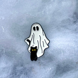 A pin badge featuring a black cat and white ghost on a blue textured background.