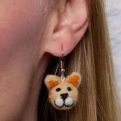 Close-up of an ear wearing a cat-shaped earring with a soft focus background.