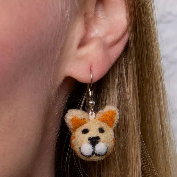 Close-up of an ear wearing a cat-shaped earring with a soft focus background.