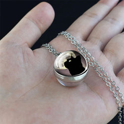 A hand holding a black cat cabochon spherical pendant
