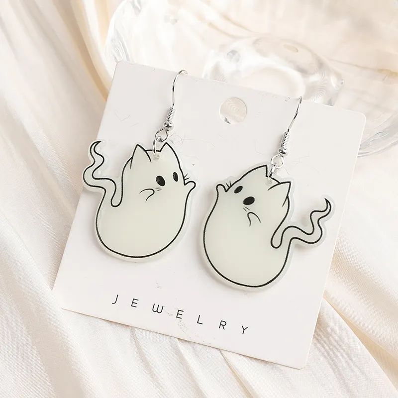 A pair of acrylic earrings designed as white ghost cats with outstretched tails, displayed on a card