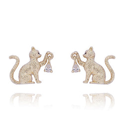 A pair of gold-toned stud earrings shaped like sitting cats holding small clear teardrop-shaped crystals