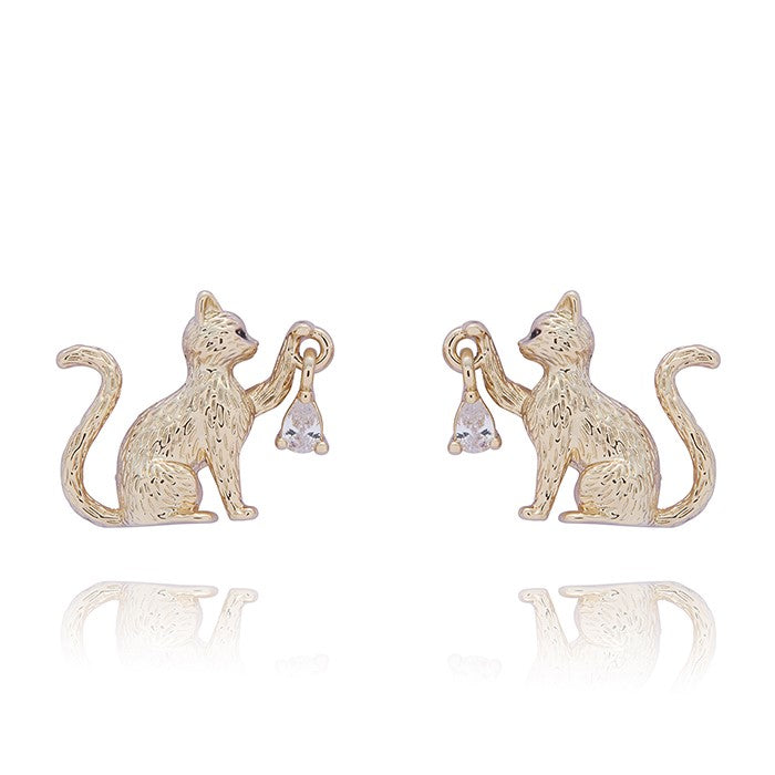 A pair of gold-toned stud earrings shaped like sitting cats holding small clear teardrop-shaped crystals