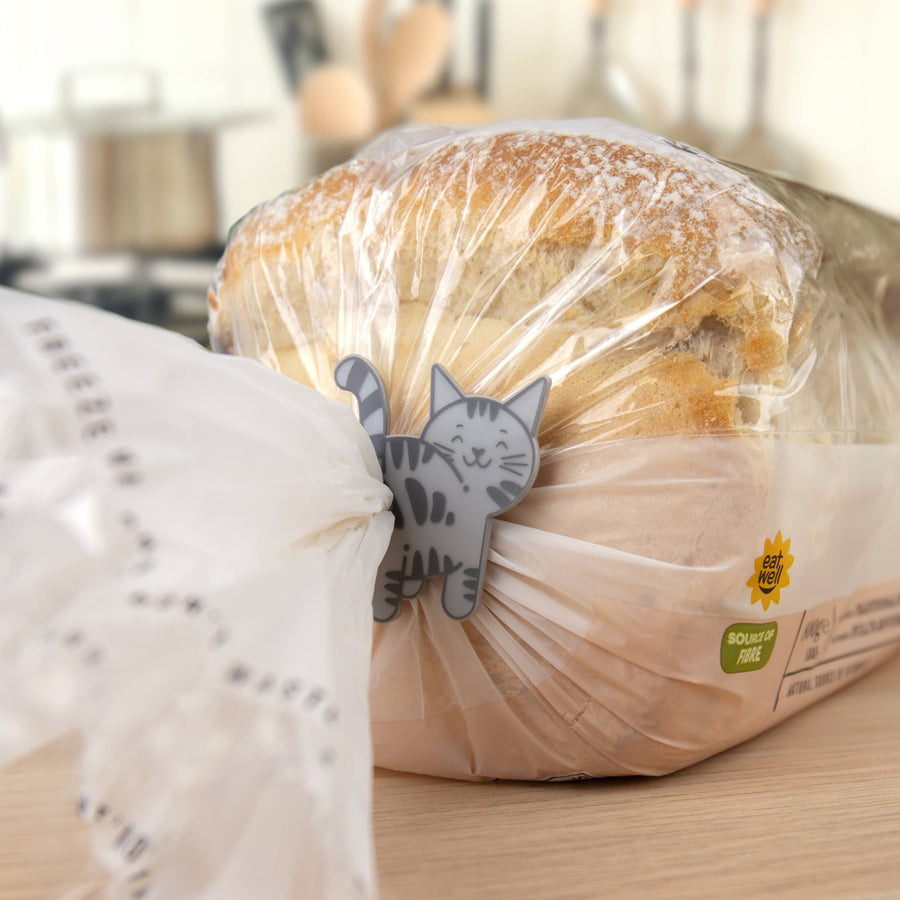 Loaf of bread wrapped in plastic with a cat-shaped tag on a kitchen counter