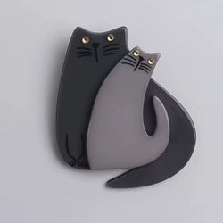 Two cat-shaped objects, one black and one grey, on a light grey background