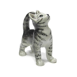 A small ceramic figurine of a grey and white tabby kitten standing on all fours and looking upward, set against a plain white background.