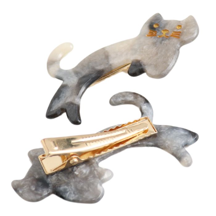 Two cat-shaped hair claw clips with marbled gray and white resin bodies and gold-tone metal clasps, shown on a plain white background.