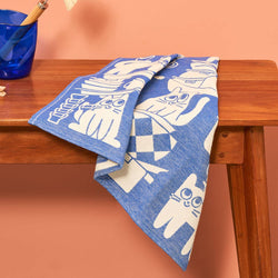 Blue towel with white cat patterns draped over a wooden surface