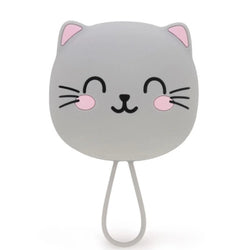 A grey cat-shaped brush with a smiling face, pink inner ears and cheeks, and black whiskers