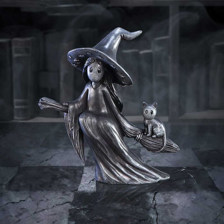 Decorative figurine of a witch with a broom and cat on a dark background