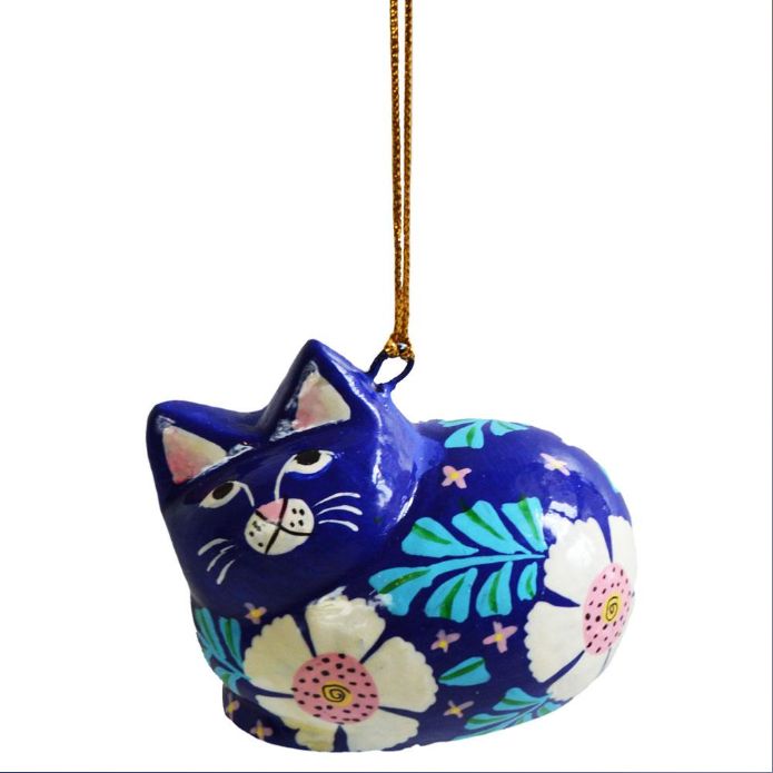 A hand-painted cat ornament in a vibrant blue color, decorated with white flowers, pink centers, and green leaves, hanging from a gold string