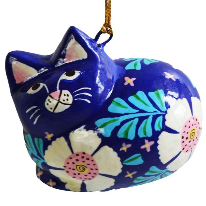 A hand-painted cat ornament in a dark blue color, decorated with white flowers, green leaves, and pink accents, hanging by a gold string