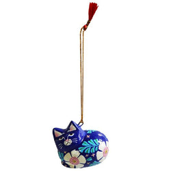 A hand-painted cat ornament in a dark blue color with white, pink, and green floral patterns, hanging from a gold-colored string with a red tassel