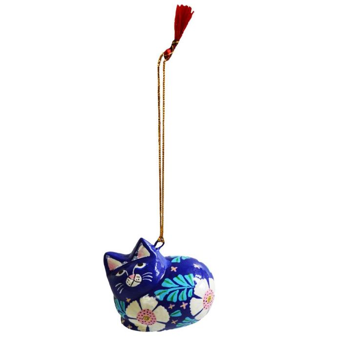 A hand-painted cat ornament in a dark blue color with white, pink, and green floral patterns, hanging from a gold-colored string with a red tassel