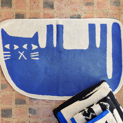 Blue and white cat-shaped rug on a brick floor