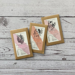 Three small kraft paper seed packets with illustrated labels including 'Romeow and Juliet' and 'The Great Catsby'