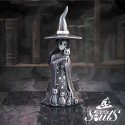 Metallic sculpture of a witch with a broomstick in a dark, gothic setting