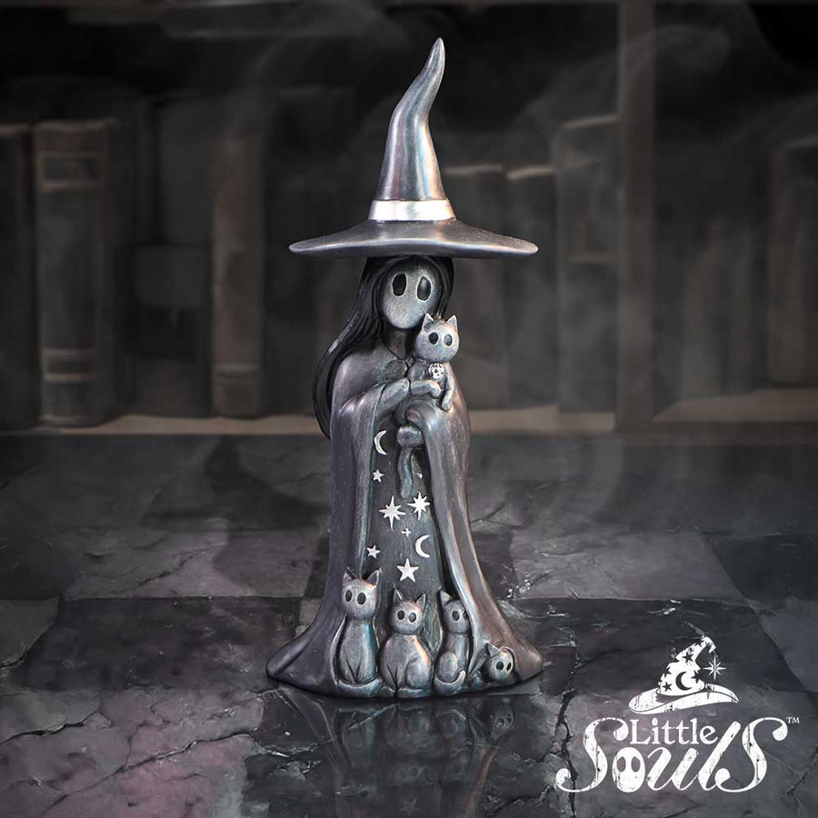 Metallic sculpture of a witch with a broomstick in a dark, gothic setting