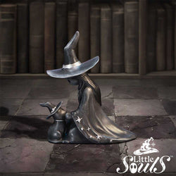 Decorative witch figurine with a hat and cape on a stone floor with books in the background, featuring the brand 'Little Souls'.