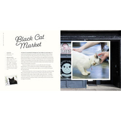 A book spread showing an article titled 'Black Cat Market' on the left and a large photo of a white cat being pet outside a shop on the right.
