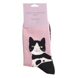 A smiling tuxedo cat with yellow eyes on a powder pink background and packaging Bamboo Socks