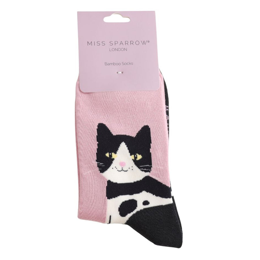 A smiling tuxedo cat with yellow eyes on a powder pink background and packaging Bamboo Socks