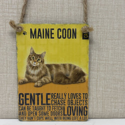 A rectangular hanging sign, featuring a painted Maine Coon cat and humorous text about the breed. The sign is suspended by a rope hanger