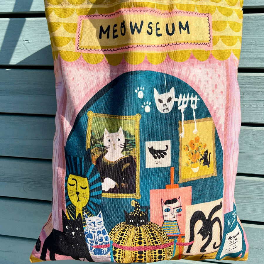 A colourful canvas tote bag with yellow handles, featuring a whimsical cat-themed illustration and the text 'MEOWSEUM'