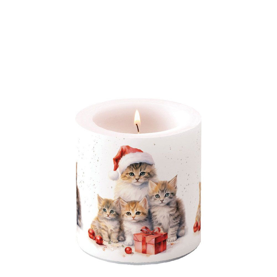 Lit candle with a design of cute tabby kittens wearing Santa hats, scattered baubles and a bow wrapped present on a white background
