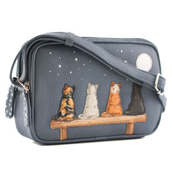 A grey pebbled leather crossbody bag featuring an illustration of four cats sitting on a bench under a starry night sky. The bag has a matching gray shoulder strap