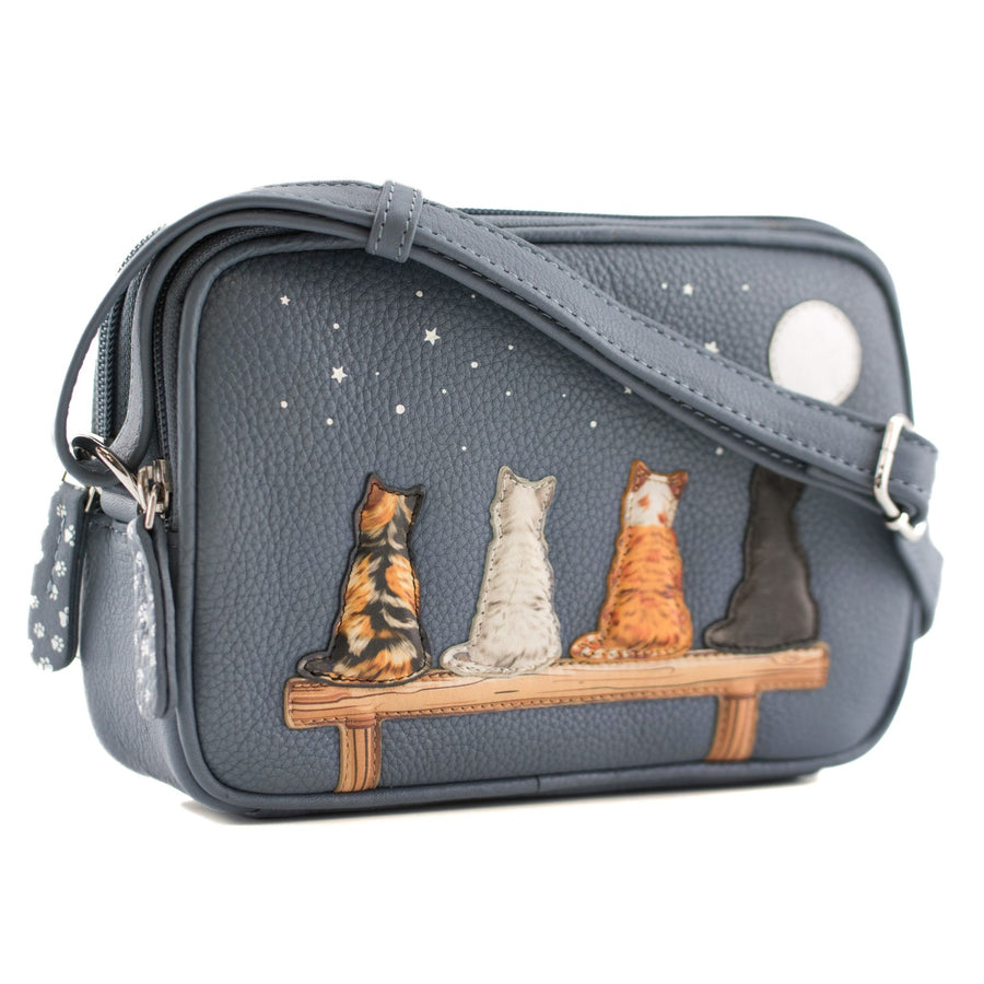 A grey pebbled leather crossbody bag featuring an illustration of four cats sitting on a bench under a starry night sky. The bag has a matching gray shoulder strap