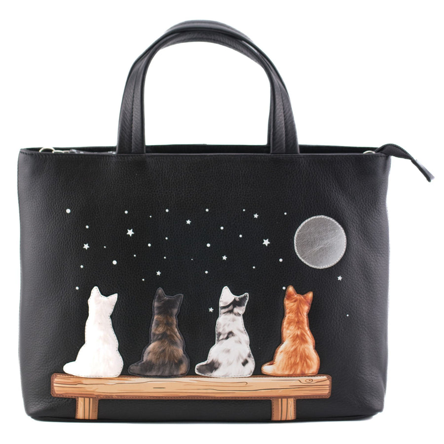 Black leather grab handbag featuring four applique cats on a bench under a moonlit starry sky