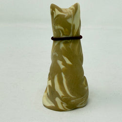 A lucky cat resin figurine shown from the back, coloured in marbled brown and cream with a dark red collar around its neck