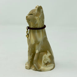 A resin lucky cat figurine in a sitting position, featuring a marbled beige and cream glaze with a dark burgundy collar and gold charm