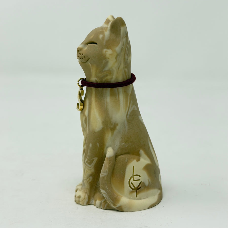 A resin lucky cat figurine in a sitting position, featuring a marbled beige and cream glaze with a dark burgundy collar and gold charm