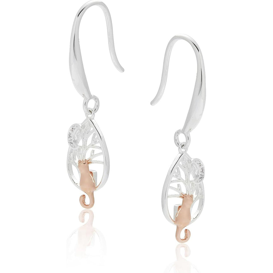 A pair of silver and rose gold dangle earrings with a tree of life design and a rose gold cat, shown on a white background with a soft reflection.