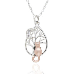 A silver teardrop pendant necklace featuring a tree design with a rose gold cat and a crescent moon, set against a plain white background.