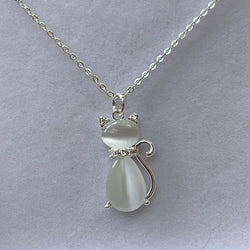 A silver-plated chain necklace with a cat-shaped pendant made of moonstone, displayed against a grey background