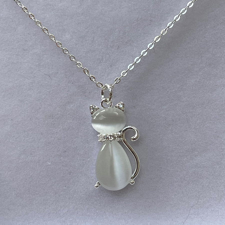 A silver-plated chain necklace with a cat-shaped pendant made of moonstone, displayed against a grey background