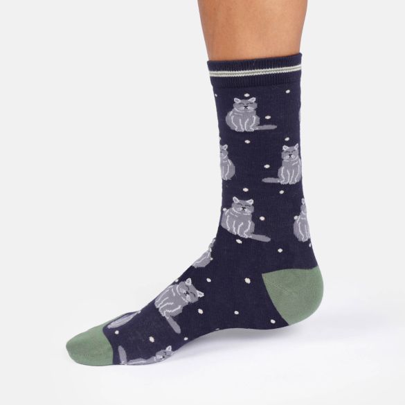 A single crew sock worn on a foot, featuring a dark navy blue background with a pattern of grey cats and white dots