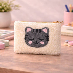 White textured pouch with a cat face design on a wooden surface