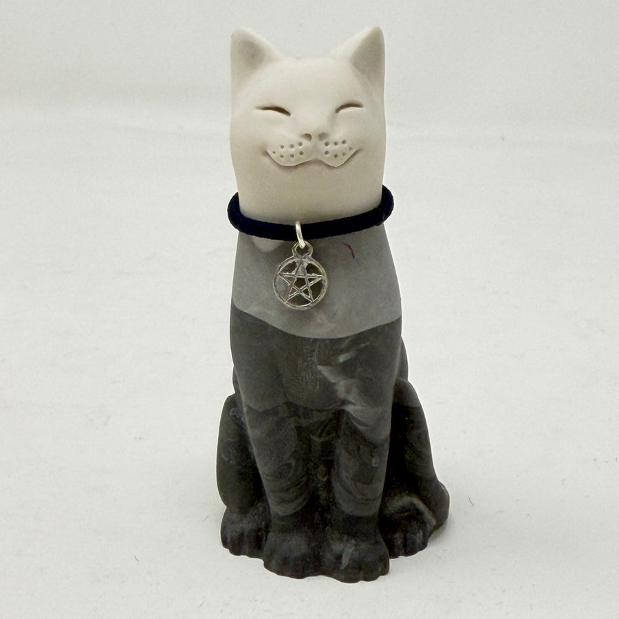 A lucky cat resin figurine, with white head and a dark grey body, wearing a black collar with a silver pentagram charm