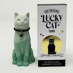A green ombre resin lucky cat figurine wearing a black collar with a green heart charm, standing next to its white and black retail box featuring gold accents and the text 'The Original Lucky Cat York'.