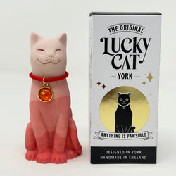 A red gradient Lucky Cat figurine wearing a red collar with a gold medallion, standing next to its white, black, and gold retail box, 'The Original Lucky Cat York'