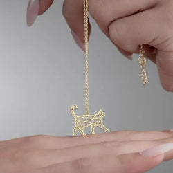 Gold geometric cat pendant on a chain on a persons hand