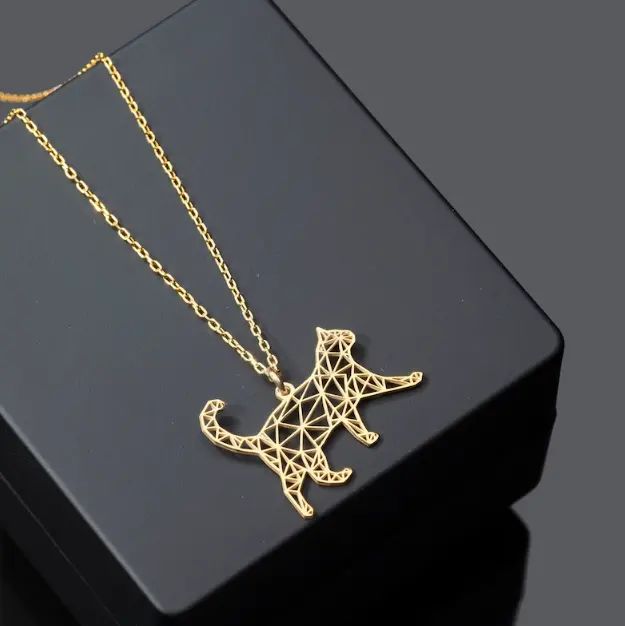 A gold-colored geometric pendant in the shape of a walking cat, displayed on a black stand with a chain.